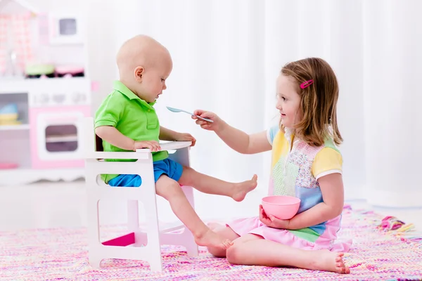 Menina alimentando bebê irmão — Fotografia de Stock