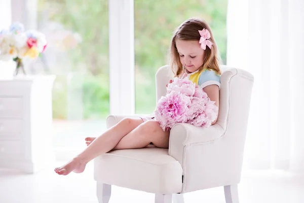 Kleines Mädchen mit Pfingstrosenblumen im weißen Schlafzimmer — Stockfoto