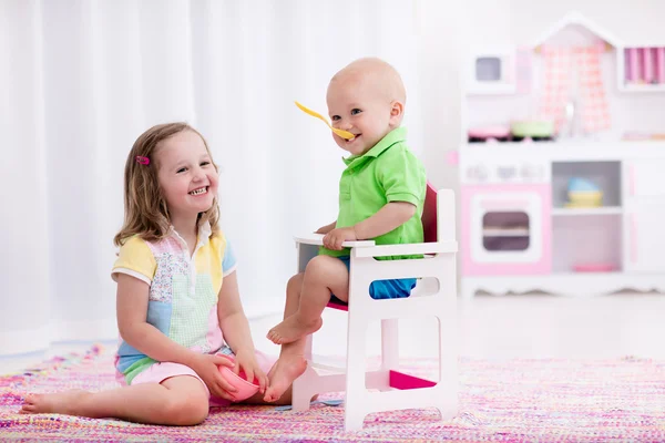 Meisje voeding baby broertje — Stockfoto