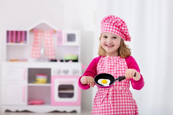 Menina brincando com cozinha de brinquedo — Fotografia de Stock