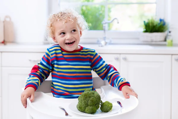 Niño comiendo brócoli en cocina blanca —  Fotos de Stock