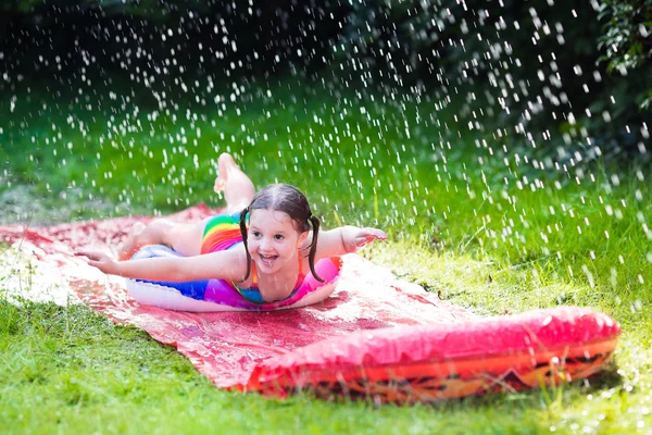 Criança brincando com corrediça de água do jardim — Fotografia de Stock