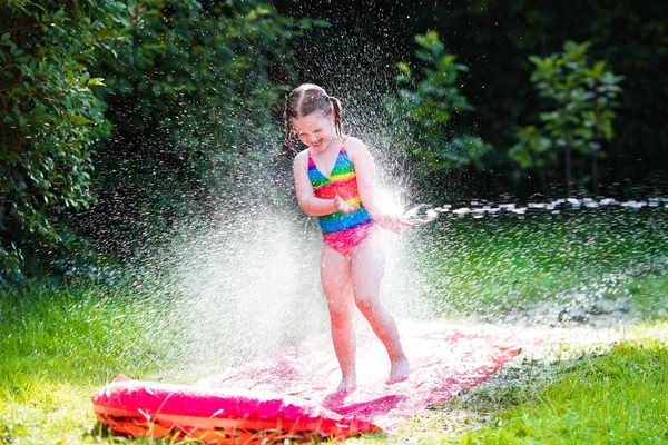 Criança brincando com corrediça de água do jardim — Fotografia de Stock