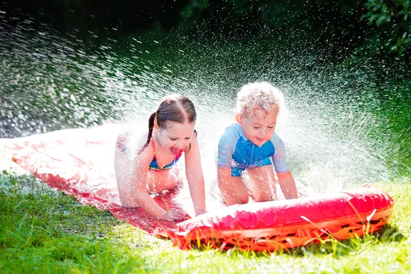 Niños jugando con tobogán de agua jardín — Foto de Stock