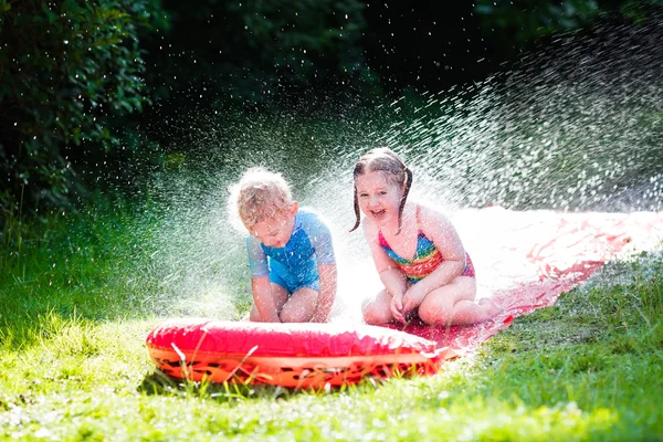 Children playing with garden water slide — Stock Photo, Image