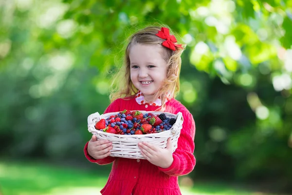 Little girl with fresh berries in a basket — Stok fotoğraf