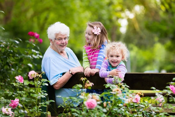 Mormor och barnen sitter i rosenträdgården — Stockfoto