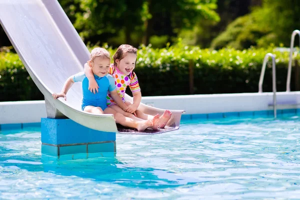 Kids on water slide in swimming pool — Stock Photo, Image