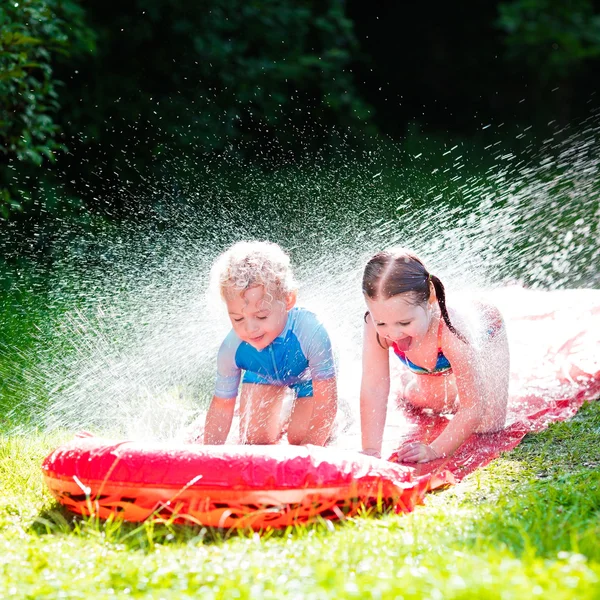 Barn som leker med trädgård vattenrutschbana — Stockfoto