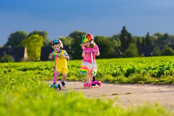 Crianças montando scooter no dia ensolarado de verão — Fotografia de Stock