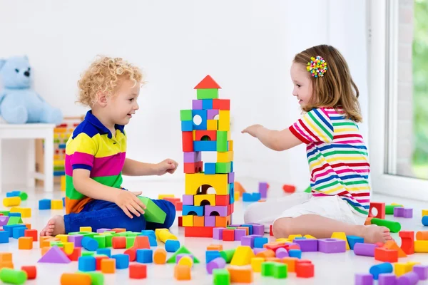 Crianças brincando com blocos de brinquedos coloridos — Fotografia de Stock