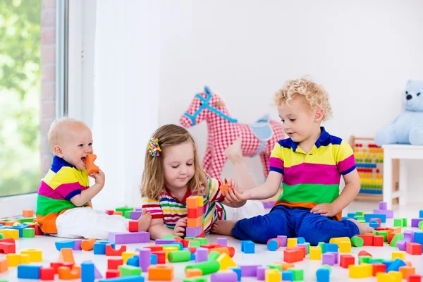 Crianças brincando com blocos de brinquedos coloridos — Fotografia de Stock