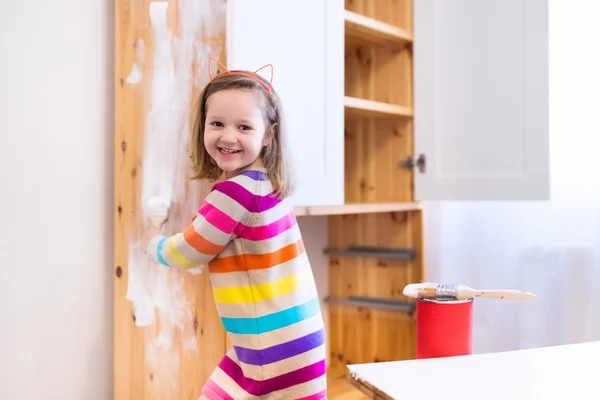 Klein meisje schilderij houten kast — Stockfoto