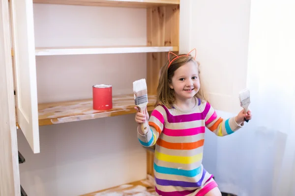 Маленькая девочка рисует деревянный шкаф — стоковое фото