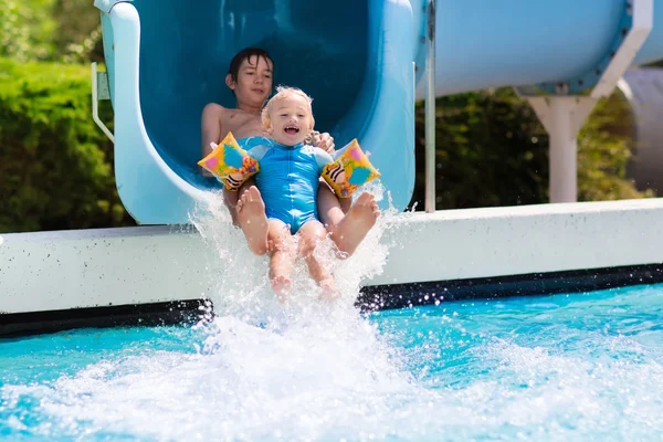 Kids on a water slide in swimming pool — Stock Photo, Image