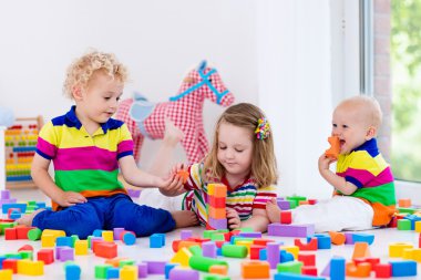 Kids playing with colorful toy blocks clipart