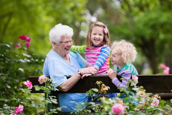Бабуся і діти сидять в трояндовому саду — стокове фото
