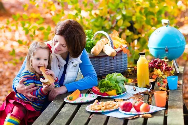 Mother and daughter set table for picnic in autumn — Stock Photo, Image