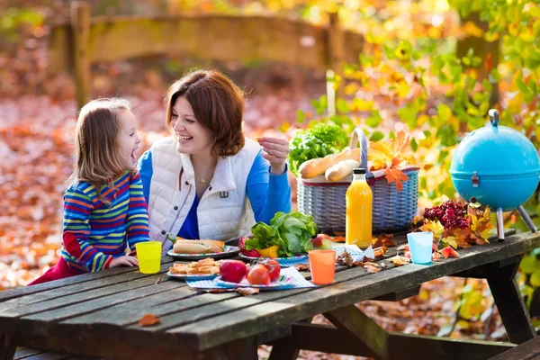 Mother and daughter set table for picnic in autumn — Stock Photo, Image