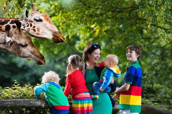 Madre e hijos alimentando jirafa en el zoológico —  Fotos de Stock