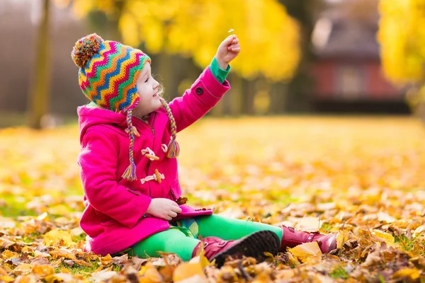 Little girl playing in autumn park — Stock Photo, Image