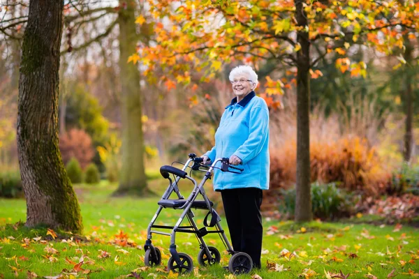 Äldre dam med en rullator i höst park — Stockfoto