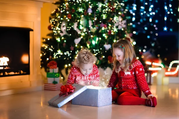 Barn öppnar julklappar vid spisen — Stockfoto