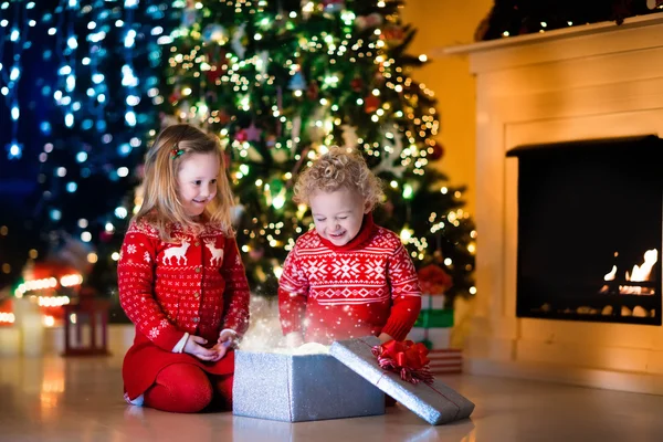 Enfants ouvrant cadeaux de Noël à la cheminée — Photo