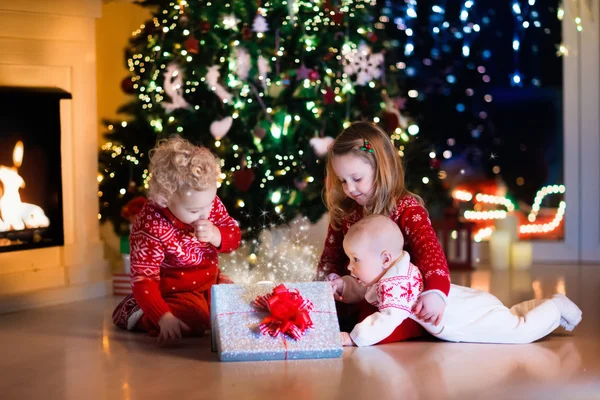 Kids opening Christmas presents at fireplace — Stock Photo, Image