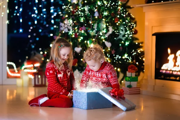 Crianças abrindo presentes de Natal na lareira — Fotografia de Stock