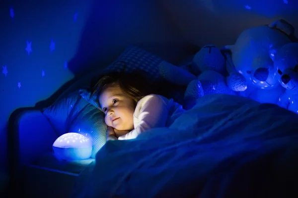 小女孩在床上的夜景灯 — 图库照片