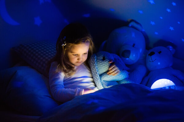 Little girl in bed with night lamp