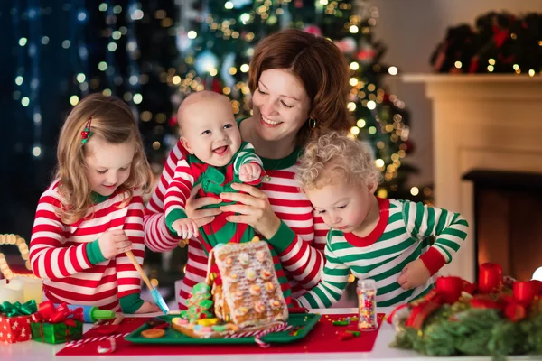 母と子供たちのクリスマスのジンジャーブレッドの家を作る — ストック写真