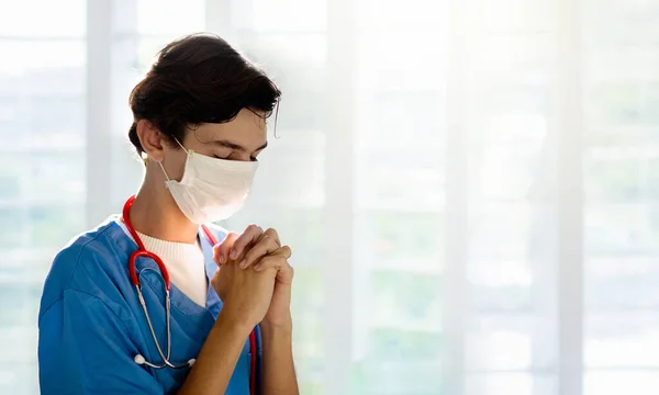 Doctor in face mask praying for XXX. Medical staff in hospital chapel or church during coronavirus outbreak. Virus pandemic. People pray. Nurse saying a prayer for sick patient.