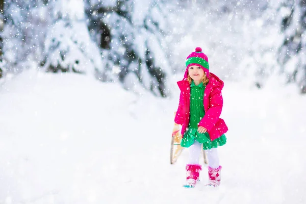 女の子はそりに乗るのを楽しんでいる 子供のそり 幼児はそりに乗っている 子供たちは雪の中屋外で遊ぶ 冬にはアルプスの山々で子供たちがそります 家族のための屋外の楽しみクリスマス休暇 — ストック写真