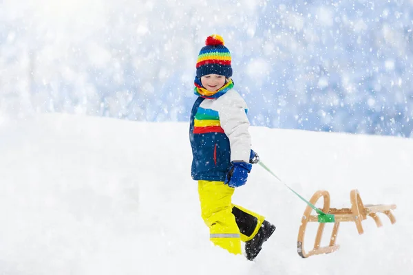 小さな男の子がそりに乗るのを楽しんでいる 子供のそり 幼児はそりに乗っている 子供たちは雪の中屋外で遊ぶ 冬にはアルプスの山々で子供たちがそります 家族のための屋外の楽しみクリスマス休暇 — ストック写真