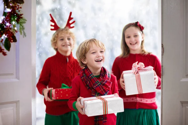 クリスマスの日に祖母を訪ねる家族 家の玄関のドアで贈り物を持つ子供たち 祖父母とクリスマスのお祝い 家の入り口にプレゼントがある子供 冬の休日のお祝い 驚きの訪問 — ストック写真