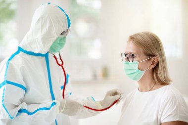 Coronavirüs için hasta hastayı muayene eden doktor. Test ve tarama için sağlık kliniğinde maskeli hasta bir kadın. Virüs tedavisi. Koronavirüs salgını. Covid-19 salgını. Kadın öksürüyor, göğüs ağrısı var..