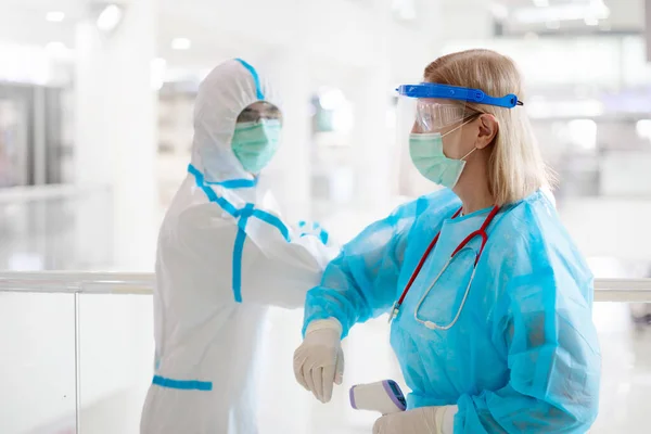 International doctor team. Hospital medical staff in hazmat suit, face shield and mask. Mixed race Asian and Caucasian doctor and nurse meeting. Clinic personnel with stethoscope. Coronavirus outbreak