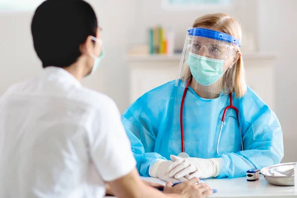 Doctor examining sick patient for coronavirus. Ill Asian man in face mask in health clinic for test and screening. Treatment of virus. Coronavirus pandemic. Covid-19 outbreak. Coughing, chest pain.