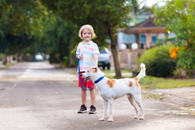 Child walking dog. Kid playing with cute puppy. Little boy running with his pet. Children play in suburban neighborhood street. Animal friends. Friendship and love. clipart