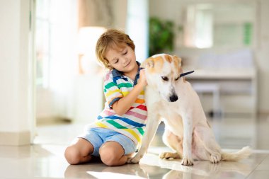 Çocuk yavru köpekle oynuyor. Çocuklar köpek yavrusuyla oynar. Küçük çocuk ve büyük köpek evde. Çocuklar ve arkadaşlık. Çocuk evcil hayvanıyla yerde oturuyor. Hayvan bakımı..