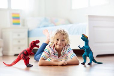 Çocuk renkli oyuncak dinozorlarla oynuyor. Çocuklar için eğitici oyuncaklar. Küçük çocuk fosil ve sürüngen öğreniyor. Çocuklar dinozor oyuncaklarıyla oynarlar. Genç çocuklar için evrim ve paleontoloji oyunu.