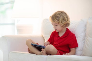 Tablet bilgisayarı olan çocuk. Çocuklar çevrimiçi çalışıyor. Evde öğrenme ve öğrenme için elektronik cihaz. Bilgisayarlı küçük çocuk. Çocuklar için Gadget ve ekran zamanı. Evdeki çocuk. Uzak okul.