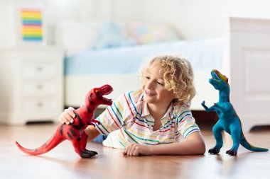 Çocuk renkli oyuncak dinozorlarla oynuyor. Çocuklar için eğitici oyuncaklar. Küçük çocuk fosil ve sürüngen öğreniyor. Çocuklar dinozor oyuncaklarıyla oynarlar. Genç çocuklar için evrim ve paleontoloji oyunu.