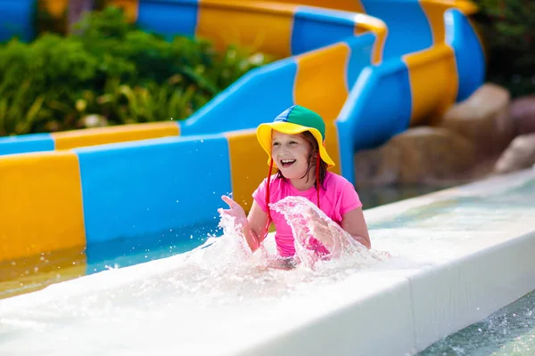 Kids on water slide in aqua park. Children having fun on water slides on family summer vacation in tropical resort. Amusement park with wet playground for young child and baby.