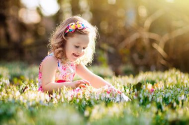 Çocuk beyaz tavşanla oynuyor. Beyaz tavşanı besleyen ve okşayan küçük bir kız. Paskalya kutlaması. Çocuk ve evcil hayvanlarla yumurta avı. Çocuklar ve hayvanlar. Çocuklar hayvanlara bakar. Bahar Paskalya Bahçesi.