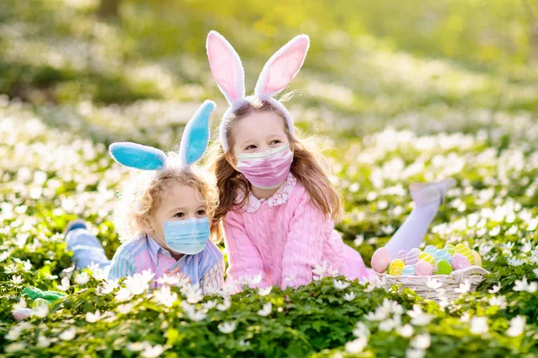 春天花园的复活节彩蛋狩猎 孩子们在花朵繁茂的田野里寻找彩蛋和糖果 有小兔子耳朵和鸡蛋篮的孩子 家庭复活节庆祝活动 男孩和女孩玩 — 图库照片