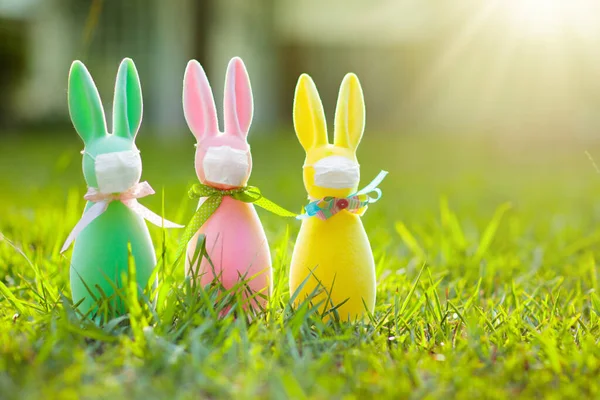 Easter bunny in face mask during coronavirus outbreak. Decoration and celebration during global virus pandemic. Easter egg hunt in flu epdemic.