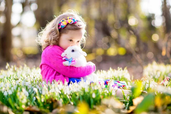 与白兔玩耍的孩子 小女孩喂白兔 爱抚白兔 复活节庆祝活动 与小孩和宠物一起猎蛋 儿童和动物 孩子们照顾宠物 春季复活节花园 — 图库照片